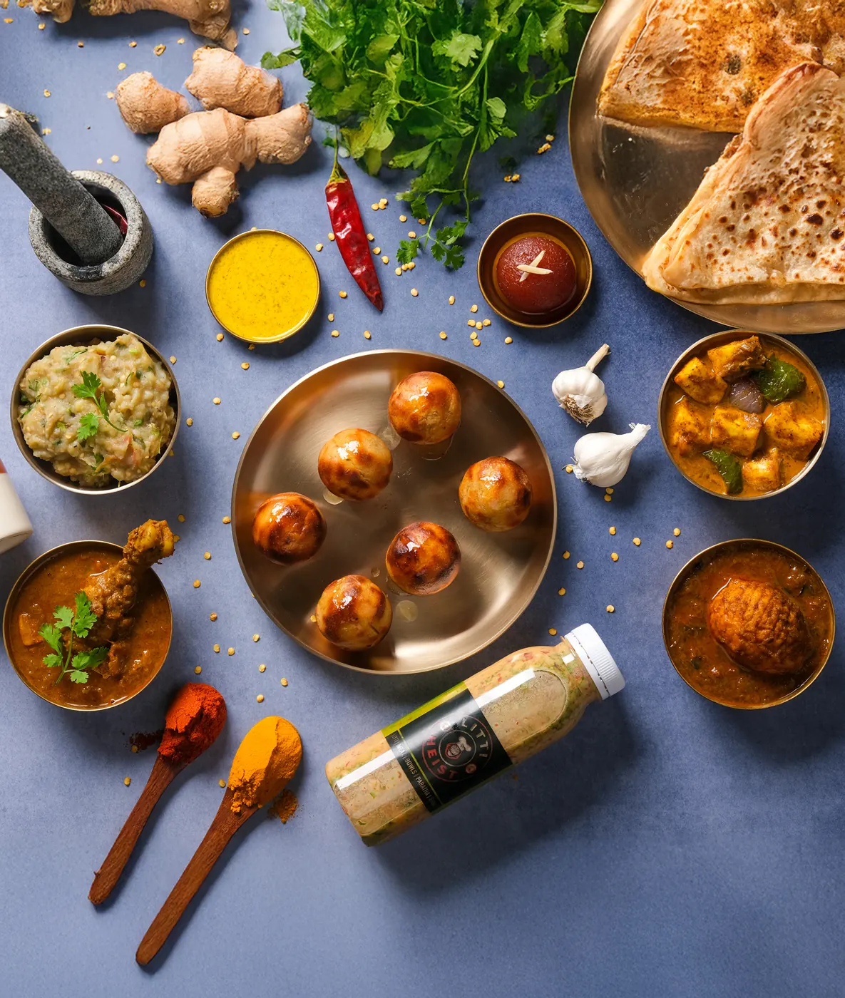 OG litti glistening with ghee on a brass plate, with chokha, curries and a sattu drink